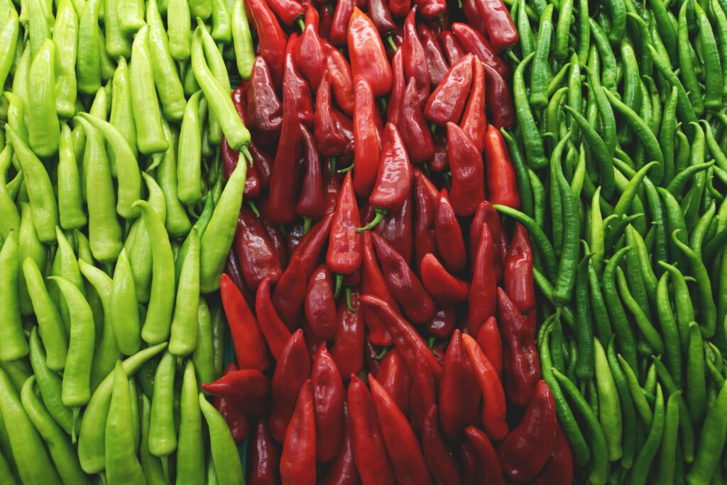 This is a close-up, high-angle shot of a beautiful, abstract arrangement of fresh peppers, featuring vibrant columns of green peppers on the left and right sides.