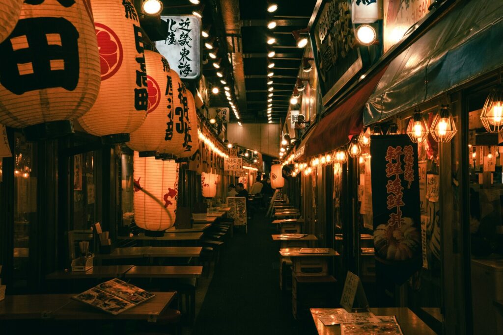 The inviting exterior of a traditional Japanese izakaya restaurant, with warm lighting and a welcoming entrance that hints at lively evenings inside