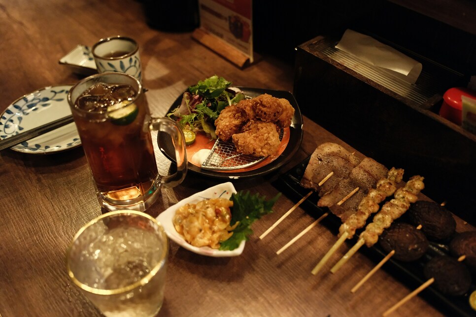 Vibrant late-night dishes served at an izakaya restaurant, featuring freshly grilled skewers and small plates under warm lights in a lively night-time setting.