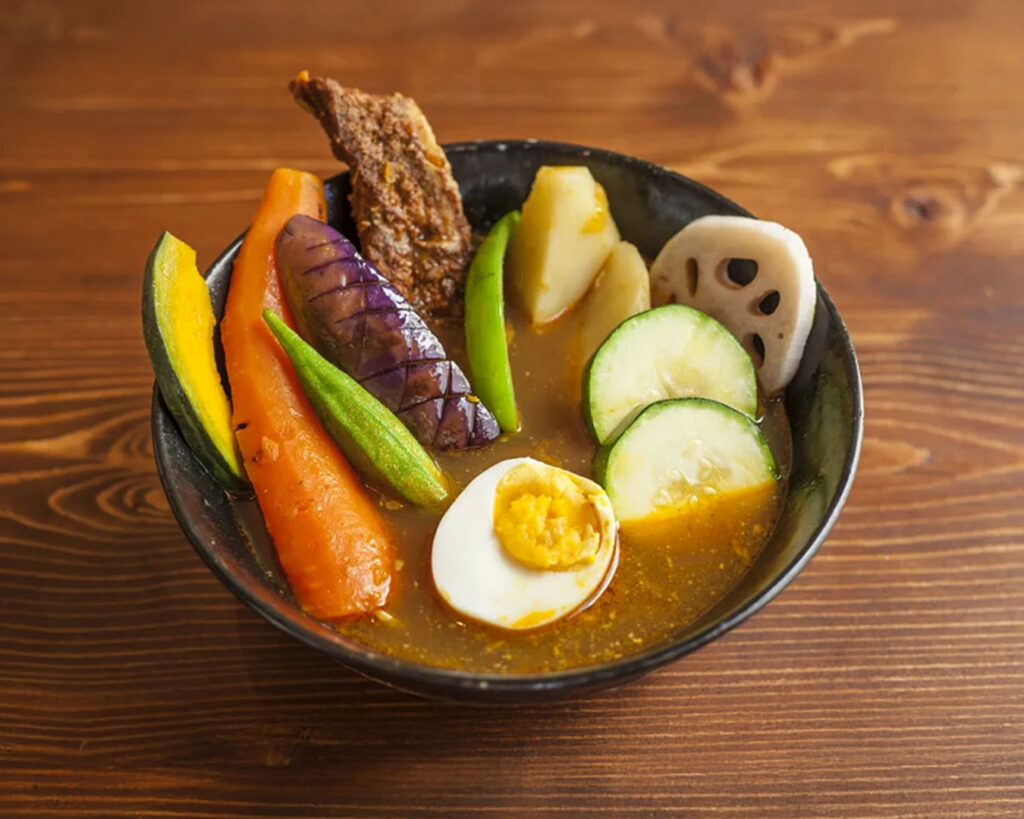 A classic bowl of Hokkaido soup curry showcasing a flavourful, slow-simmered broth infused with Japanese spices, paired with tender proteins and seasonal vegetables for a comforting and hearty meal.
