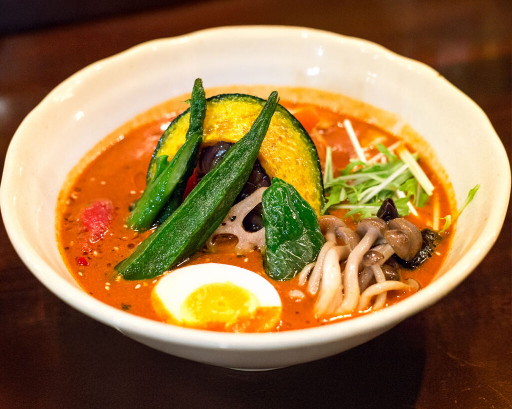 This is a high-angle photograph of a Japanese-style curry dish, featuring rice and chunks of meat and vegetables in a savory brown sauce on a large white plate.