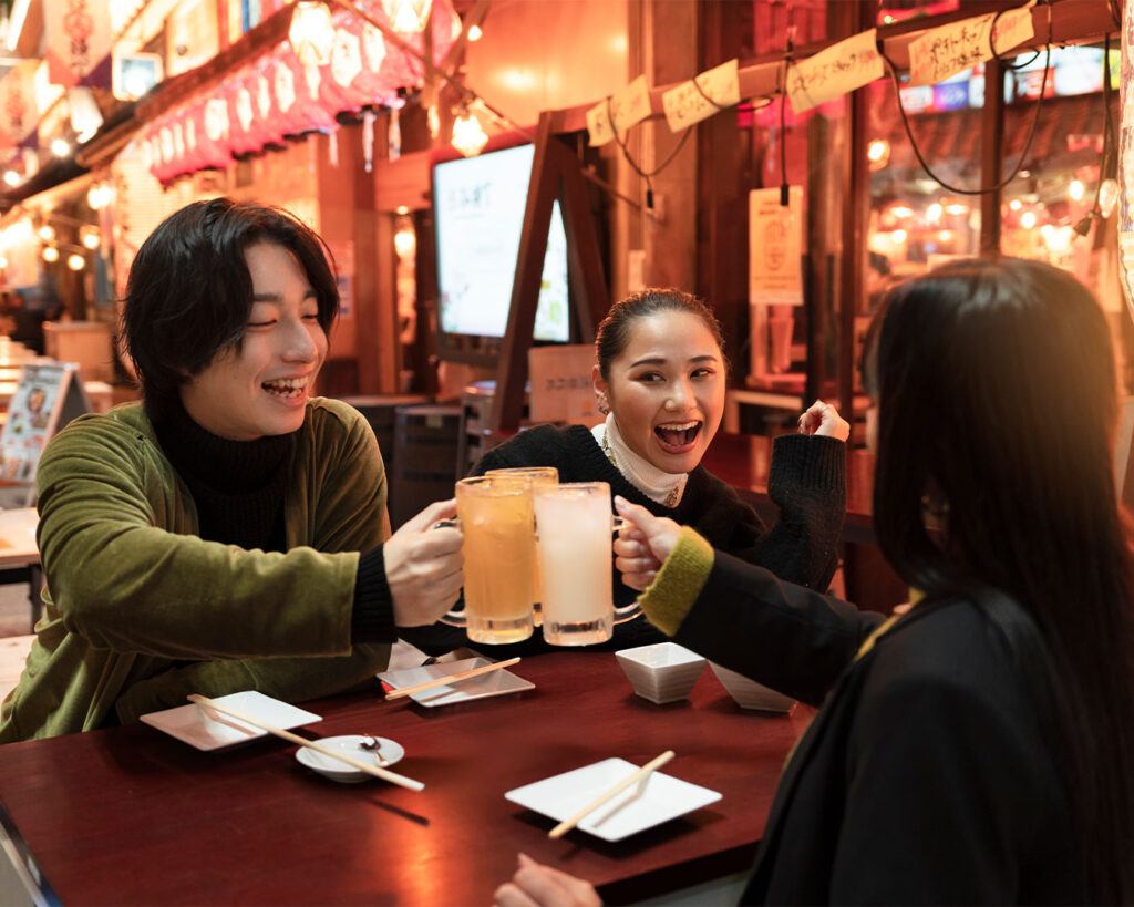 A lively group sharing dishes and drinks at an izakaya after work, surrounded by warm tones and bustling energy that reflects the social heart of Japanese dining culture.