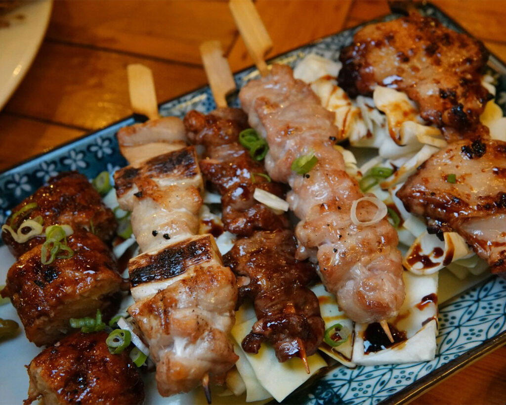 Close-up of chicken skewers resting on a minimalist table, the golden-brown surface highlighting careful grilling and artisanal preparation, evoking warmth and comfort.