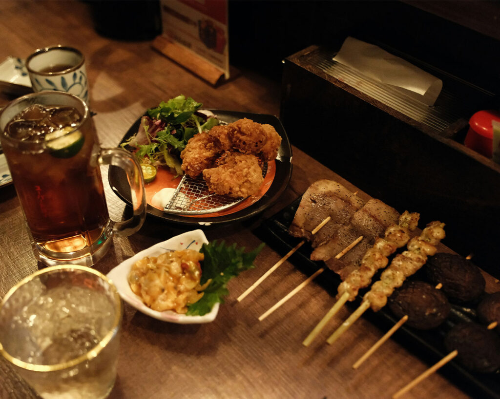 Vibrant late-night dishes served at an izakaya restaurant, featuring freshly grilled skewers and small plates under warm lights in a lively night-time setting.
