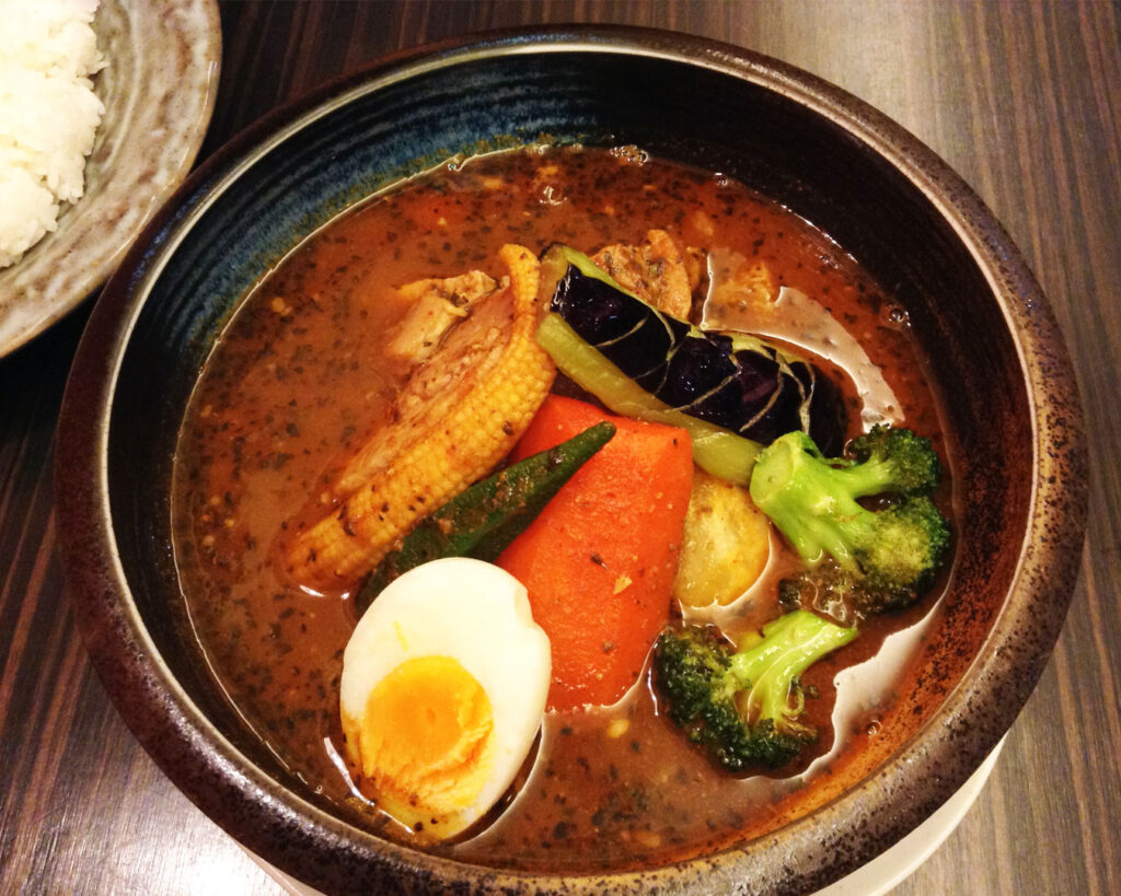 Fragrant Hokkaido soup curry served alongside fluffy Japanese rice, creating a perfectly balanced and satisfying meal.