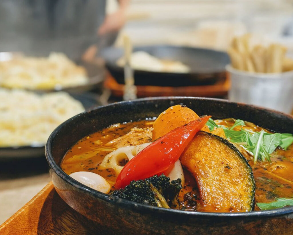 Traditional Hokkaido-style soup curry with a richly spiced broth, offering warmth, depth, and comforting umami in every spoonful.