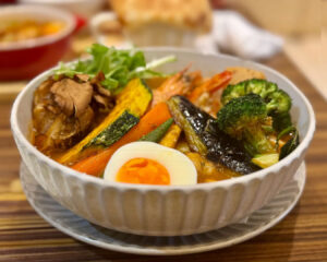 A bowl of soup curry with vegetables and meat, served in a restaurant setting in Singapore.