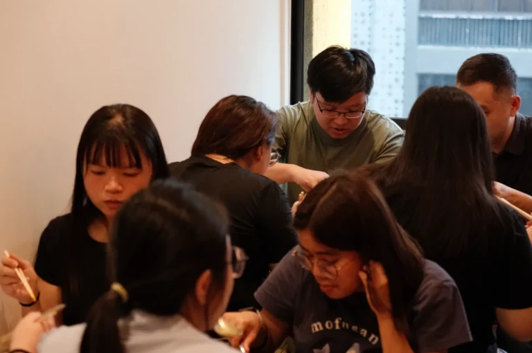 A group of people sitting around a table, eating and enjoying a meal together.