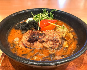 A steaming bowl of Japanese soup curry filled with vibrant vegetables and tender ingredients, served in a deep ceramic bowl for a comforting presentation.