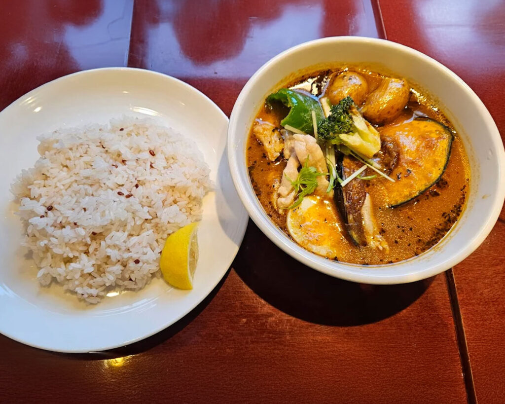 A bowl of soup curry served alongside fluffy white rice, ready to be enjoyed together.