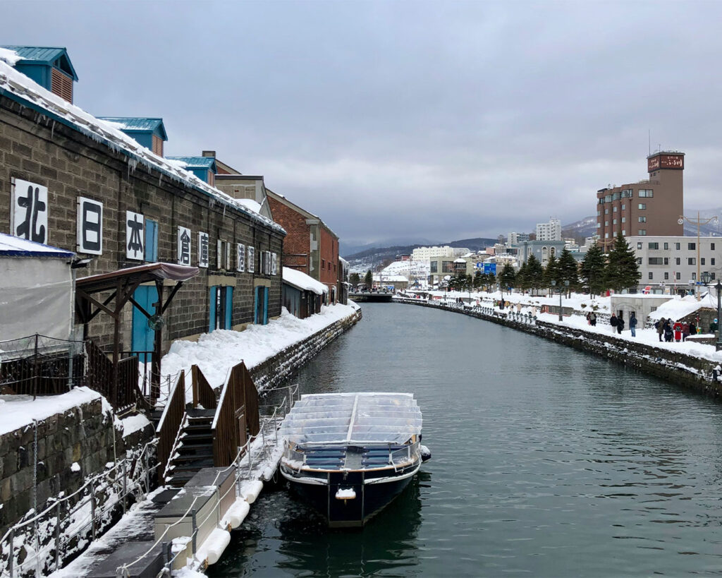 A quiet river in Hokkaido surrounded by snow-covered trees and banks, creating a calm winter landscape.