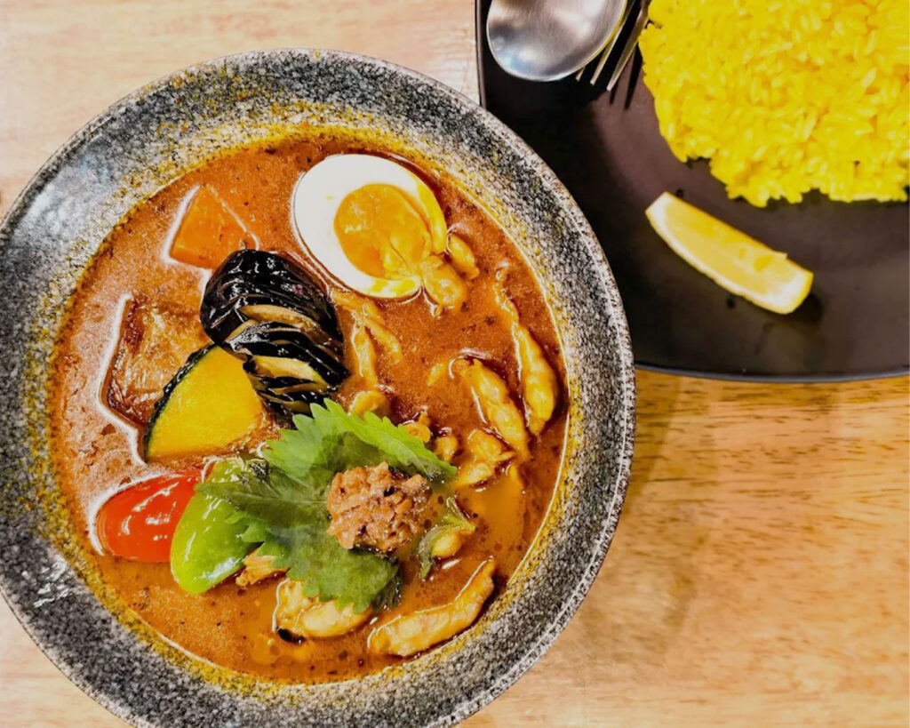 A vibrant bowl of Japanese soup curry filled with tender chicken, carrots, potatoes, and rich, spiced broth.