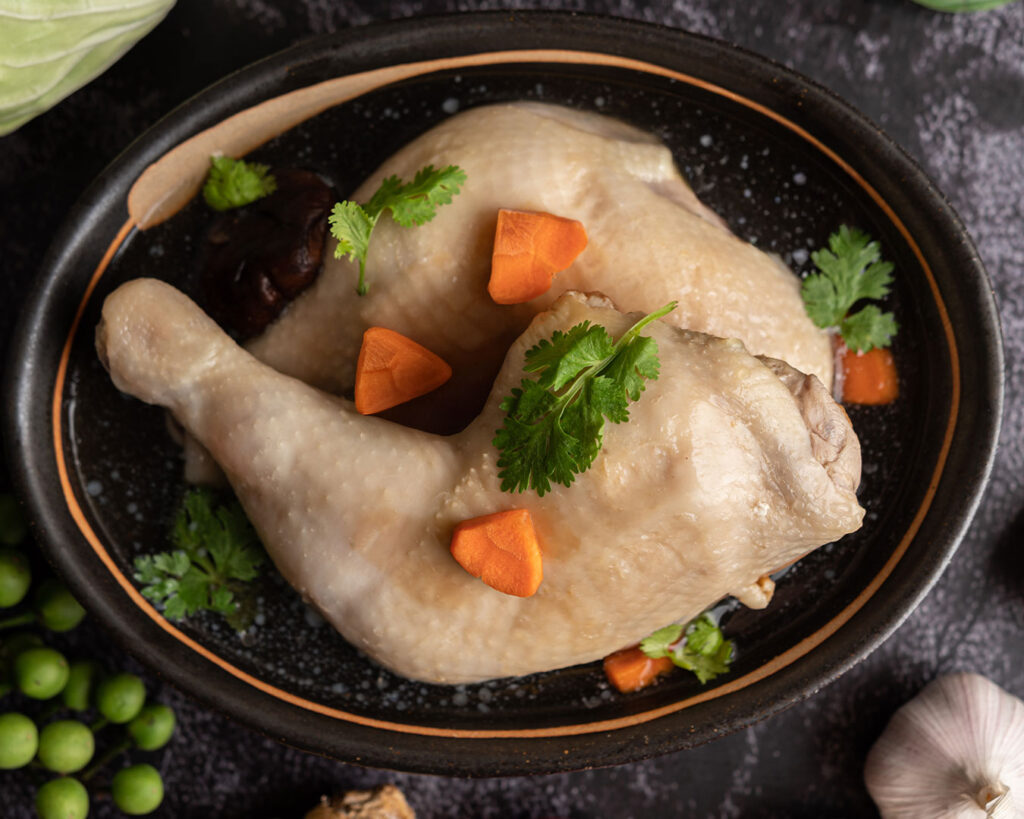 A close-up of chicken soup curry with soft chicken pieces, potatoes, carrots, and fragrant spices floating in a clear, savoury broth.