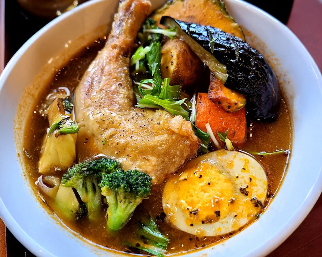 A steaming bowl of Sapporo soup curry filled with rich broth, vegetables, and tender meat.
