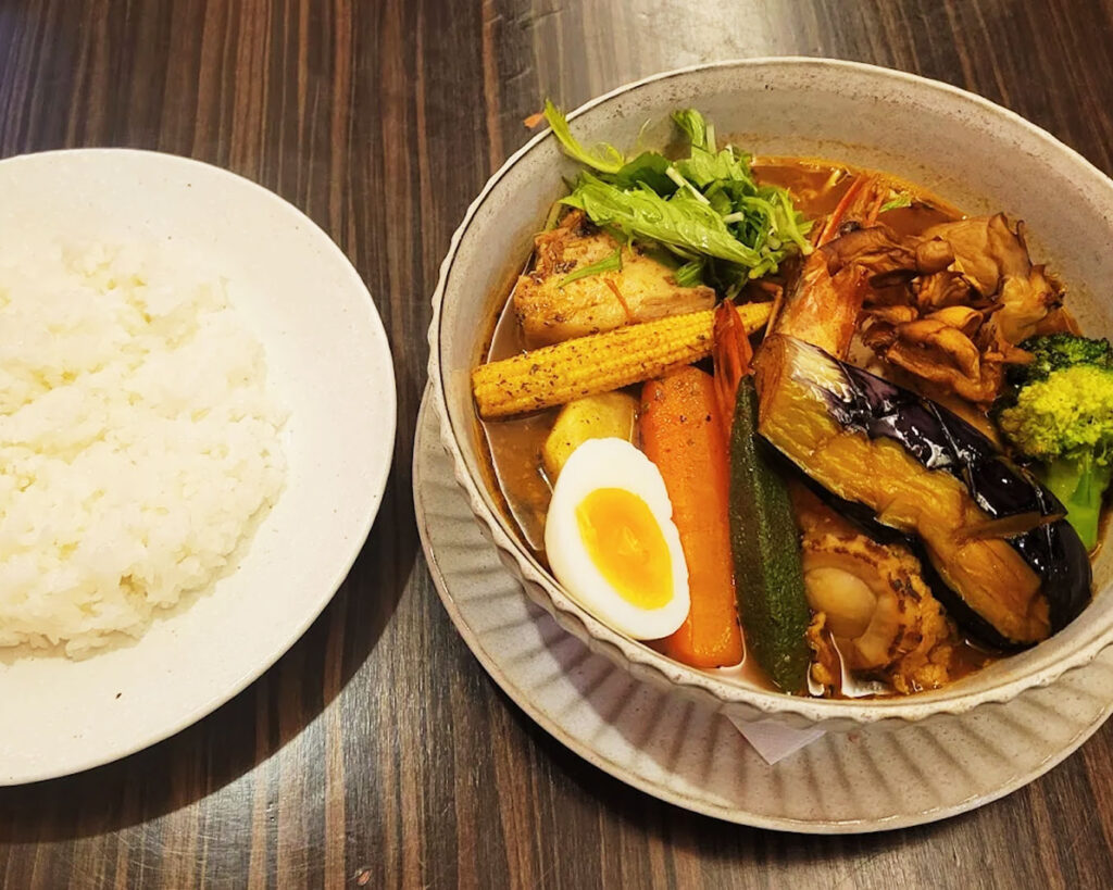 Soup curry served alongside a bowl of rice, creating a complete and satisfying meal set.
