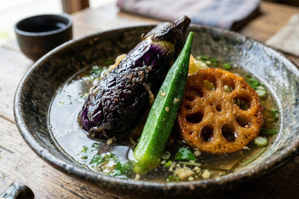 A close-up of Japanese soup curry featuring a charred eggplant, a whole okra pod, and a fried lotus root slice in a savory brown broth.