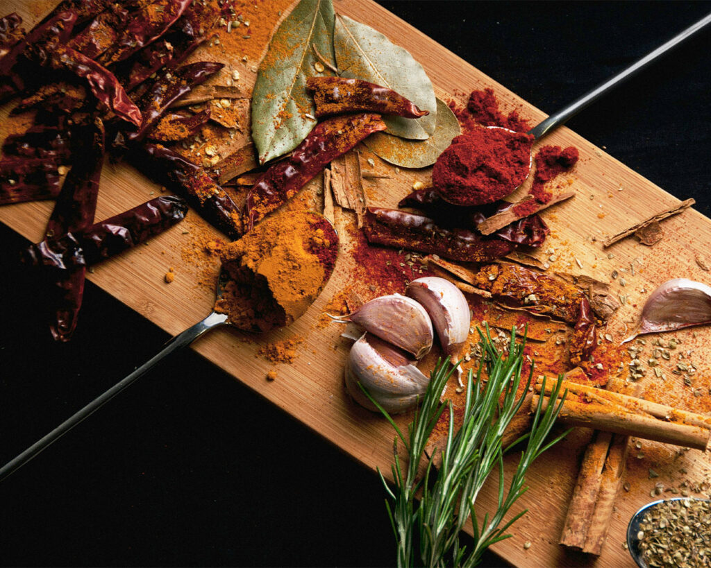 An arrangement of assorted spices in small bowls, displaying vibrant colours and textures used in making soup curry