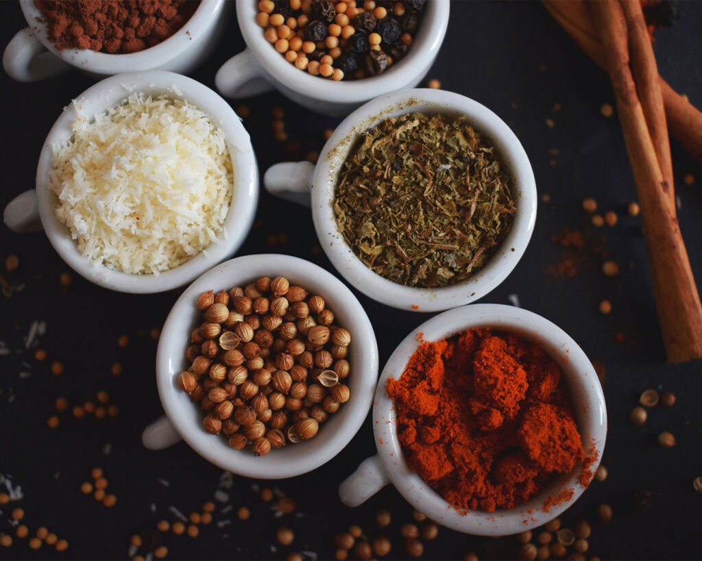 Assorted spices used for soup curry displayed in small bowls, showing their vibrant colours and aroma.