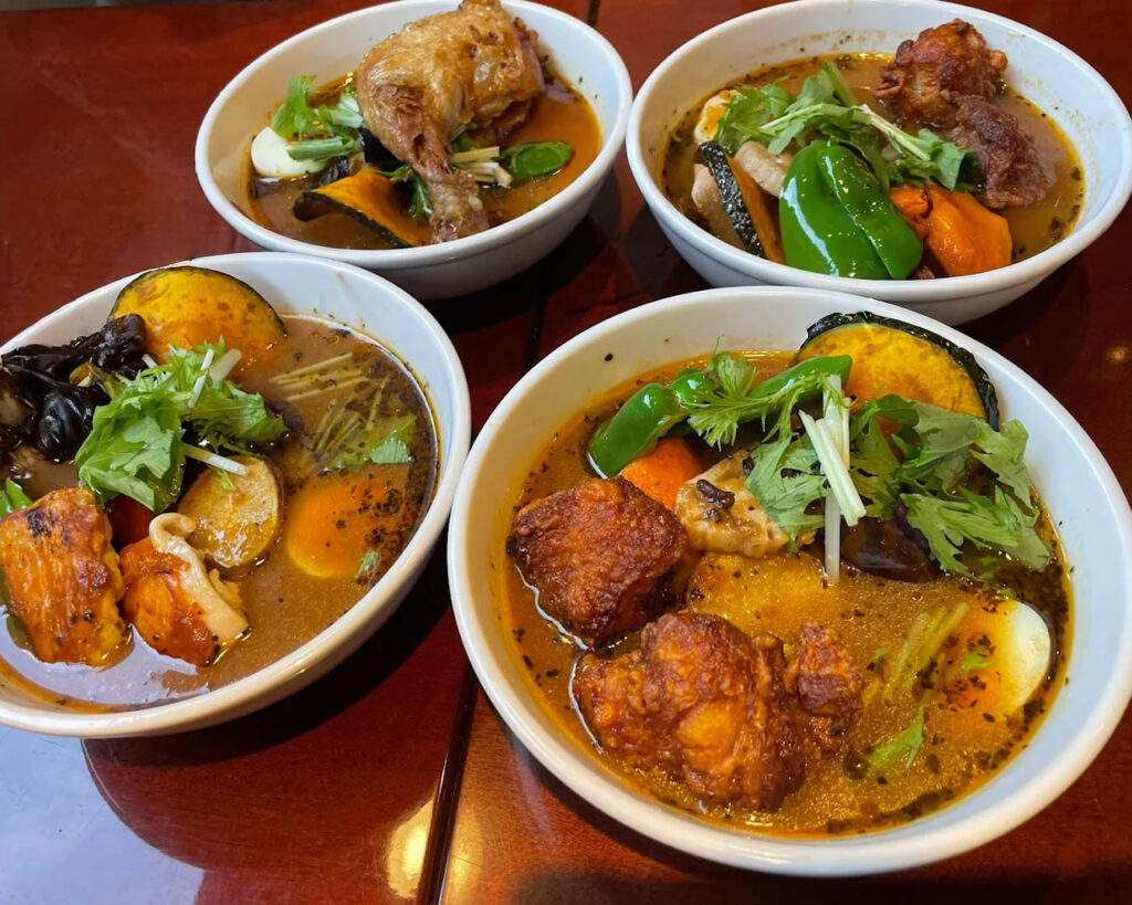 Multiple bowls of soup curry with varied ingredients and spice levels, showcasing the diversity of the dish