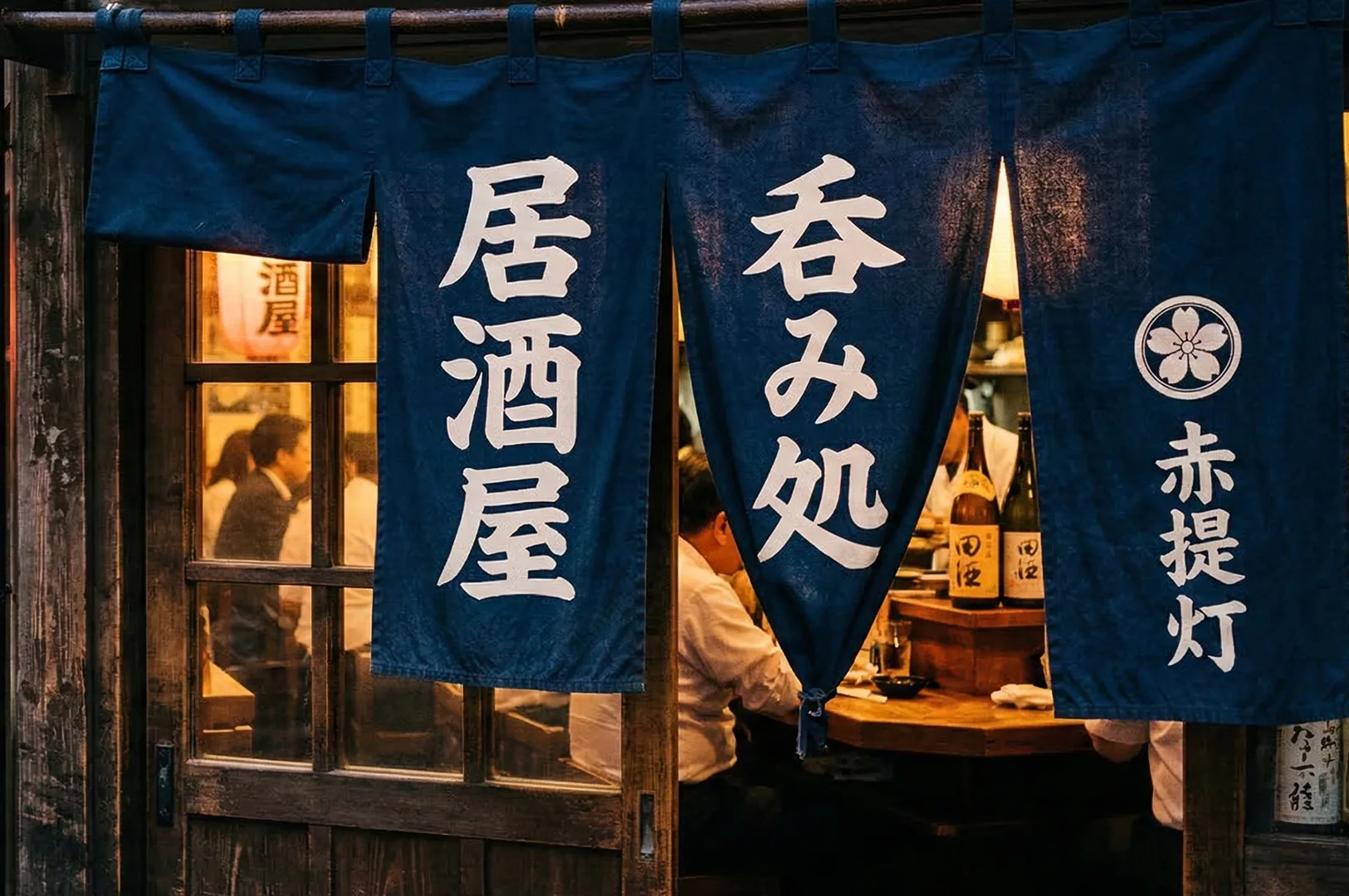 Blue noren curtains with Japanese kanji at the entrance of a traditional Izakaya restaurant in Japan.