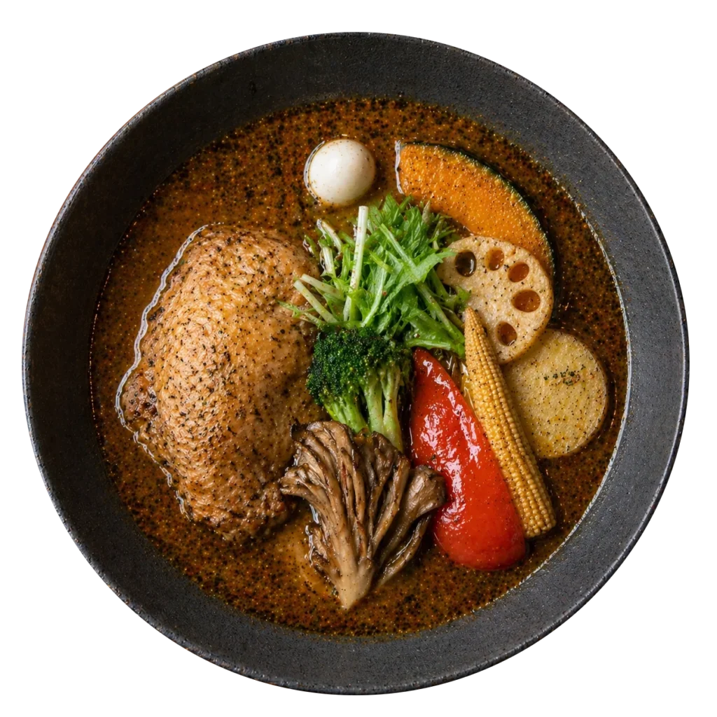 Overhead view of authentic Hokkaido soup curry in a dark stone bowl featuring chicken and fresh vegetables.