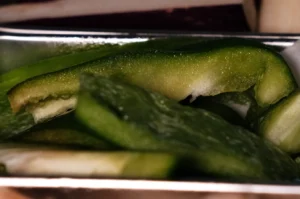 Close-up shots of slices of green bell pepper in a metla container.