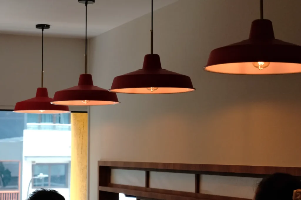 A row of red pendant lights hanging from the ceiling in a modern indoor setting.