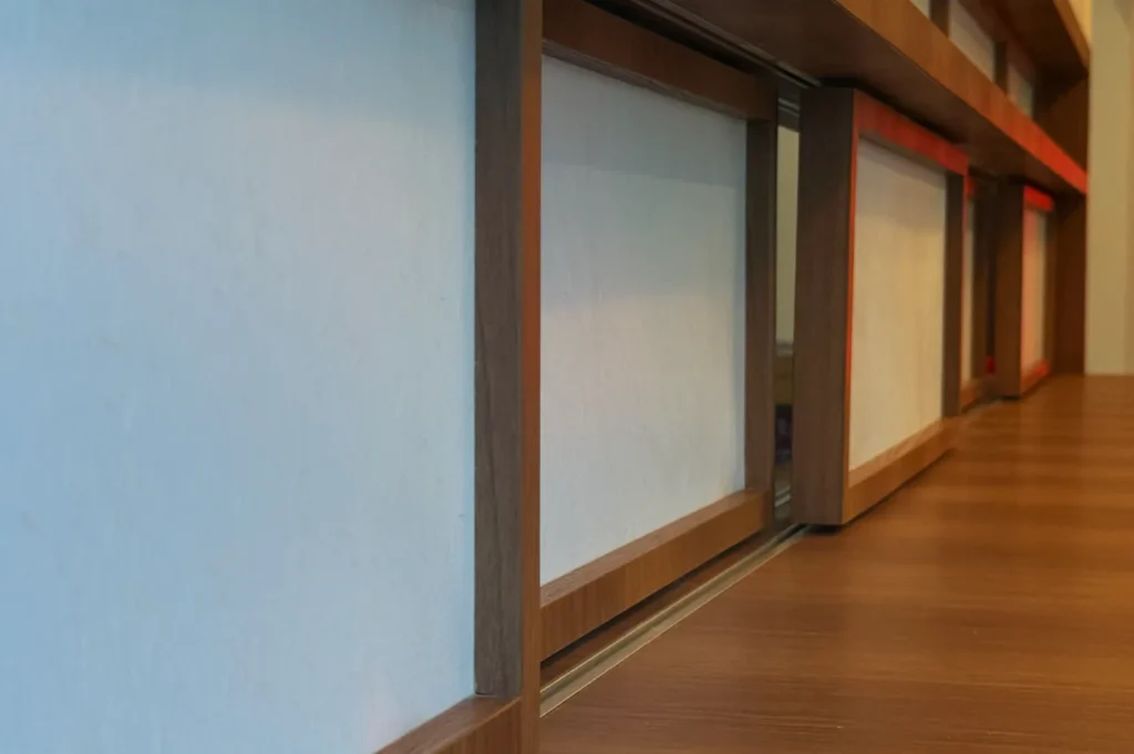 A close-up view of a wooden surface with a recessed shelf or display area, featuring a light-colored wall behind it.