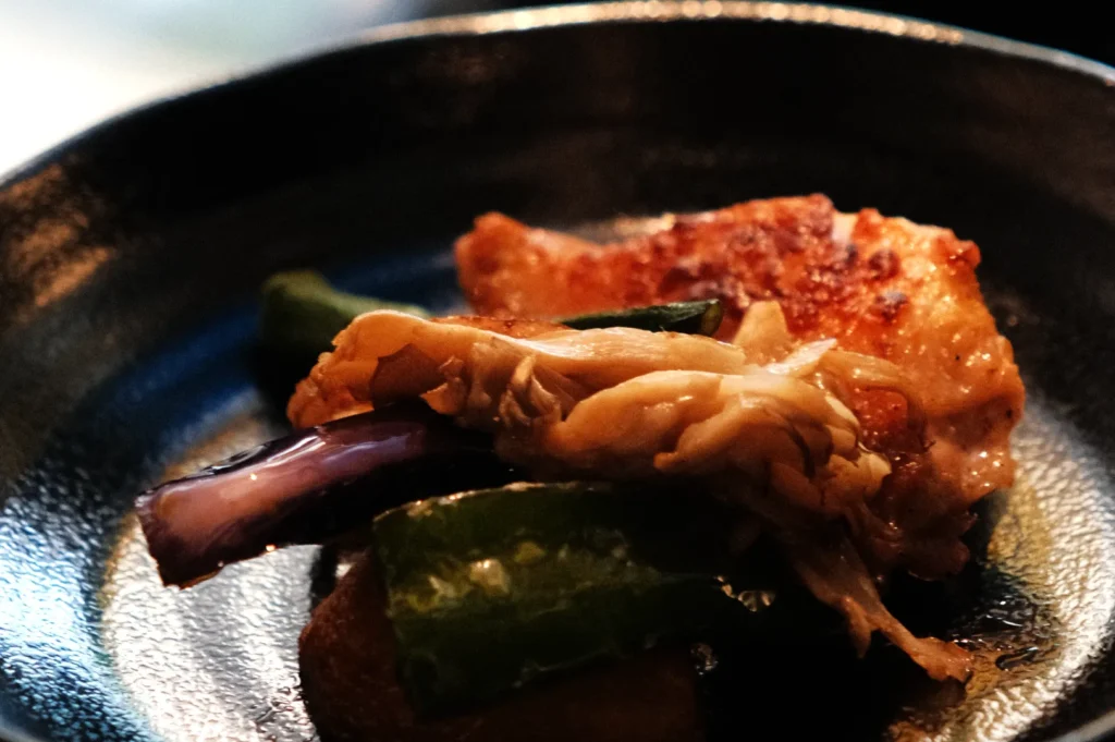 A plate of sautéed chicken with vegetables, including green bell peppers and purple eggplant.