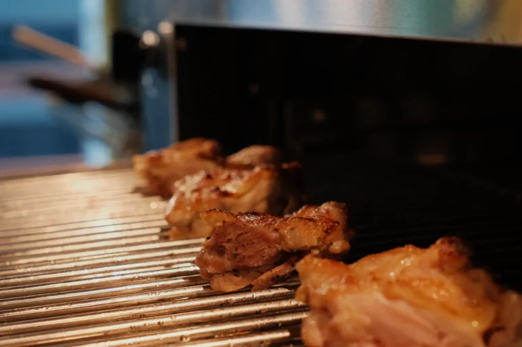 Grilled chicken pieces on a barbecue grill.