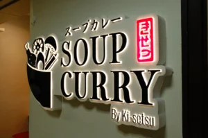 Sign for a restaurant named "SOUP CURRY" by Ki-setsu, featuring a graphic of a bowl with curry ingredients.