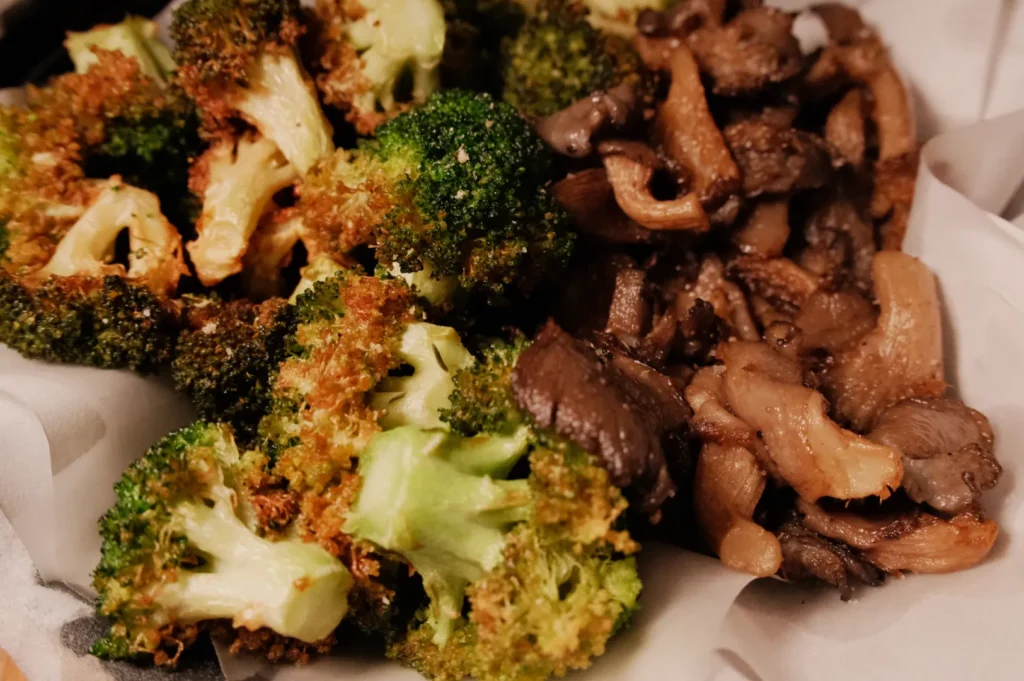A close-up of roasted broccoli and sautéed mushrooms on a plate.