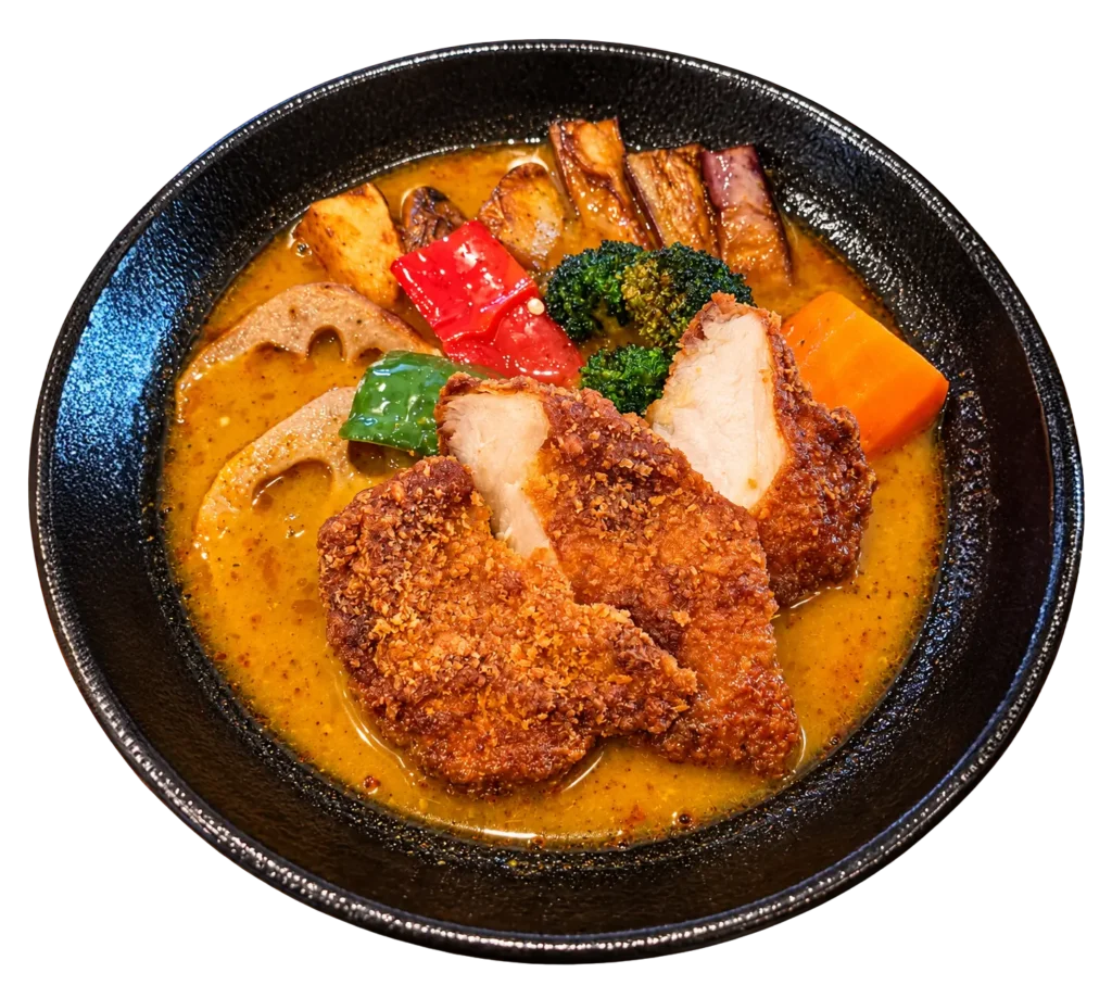 A bowl of curry featuring grilled meat, vegetables like broccoli and okra, sliced lotus root, and a boiled egg.
